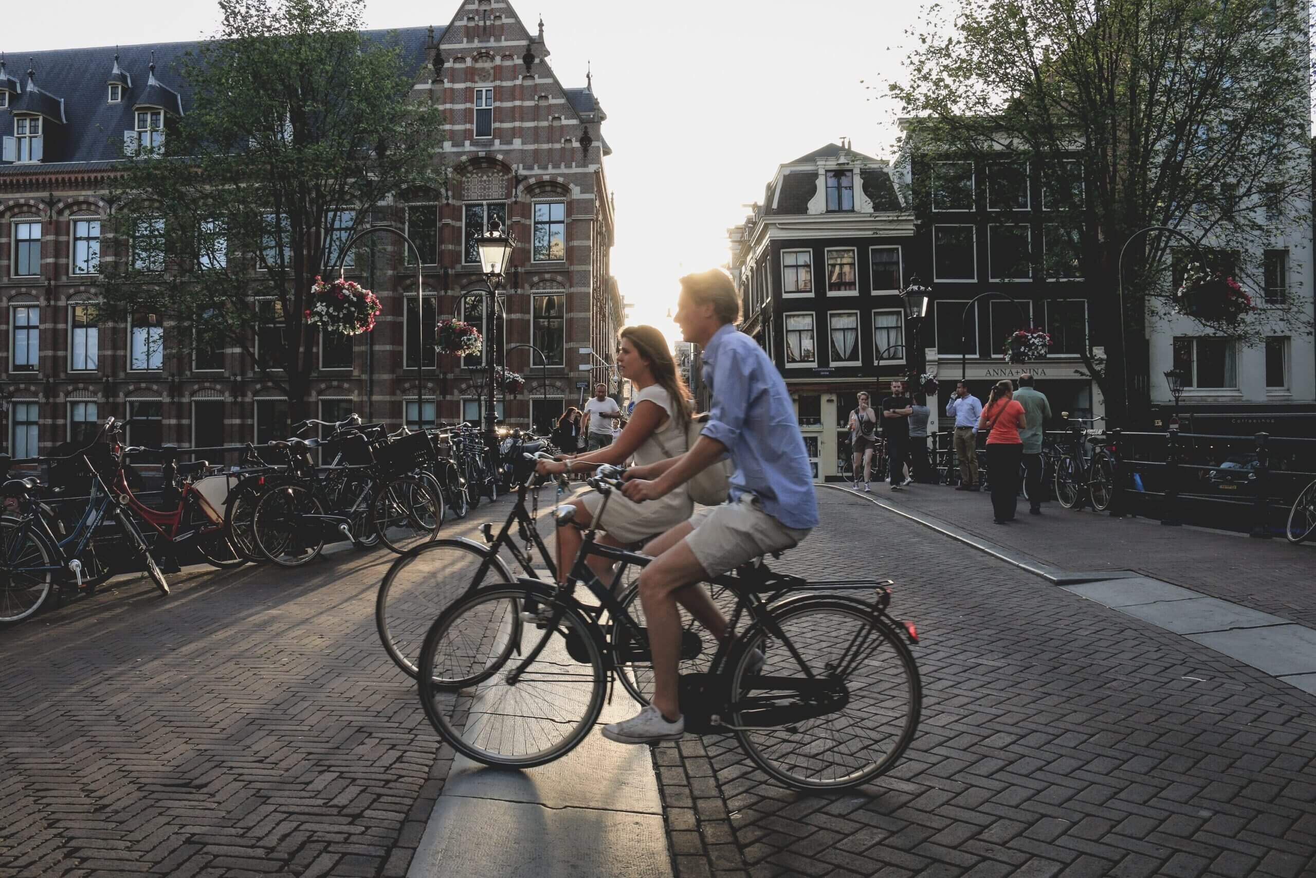 two cyclists riding on the streets of Amsterdam, one of the best fall destinations
