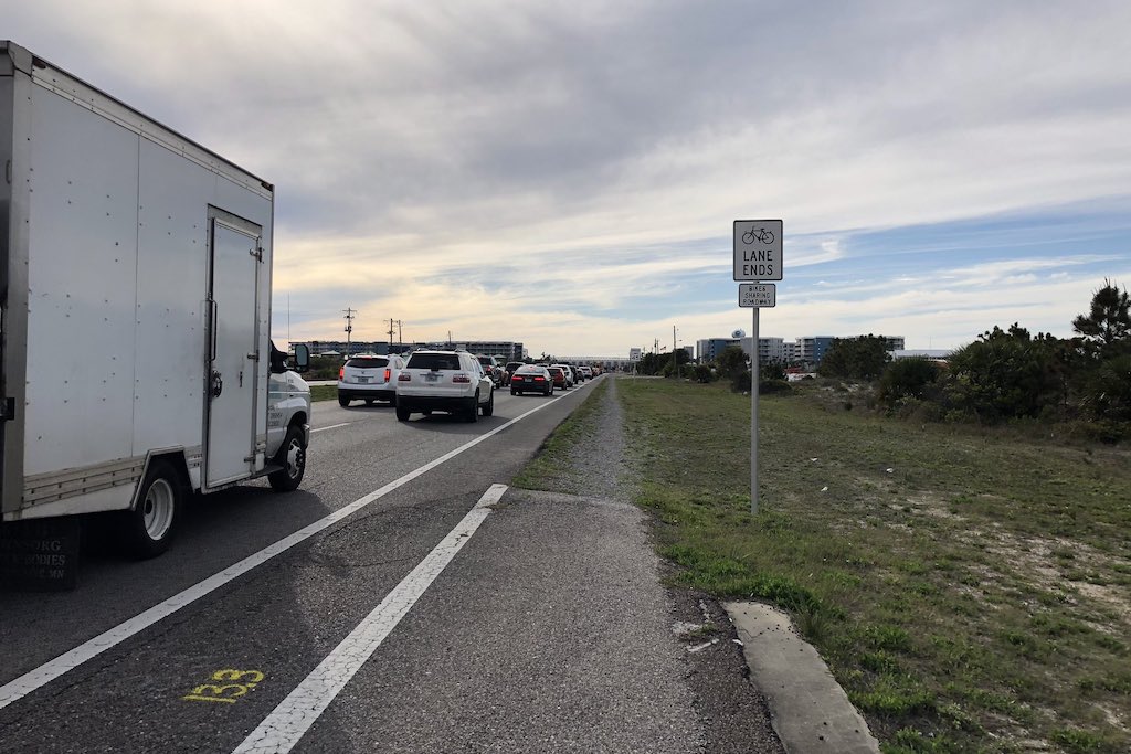 A highway packed with cars and a very narrow bike lane